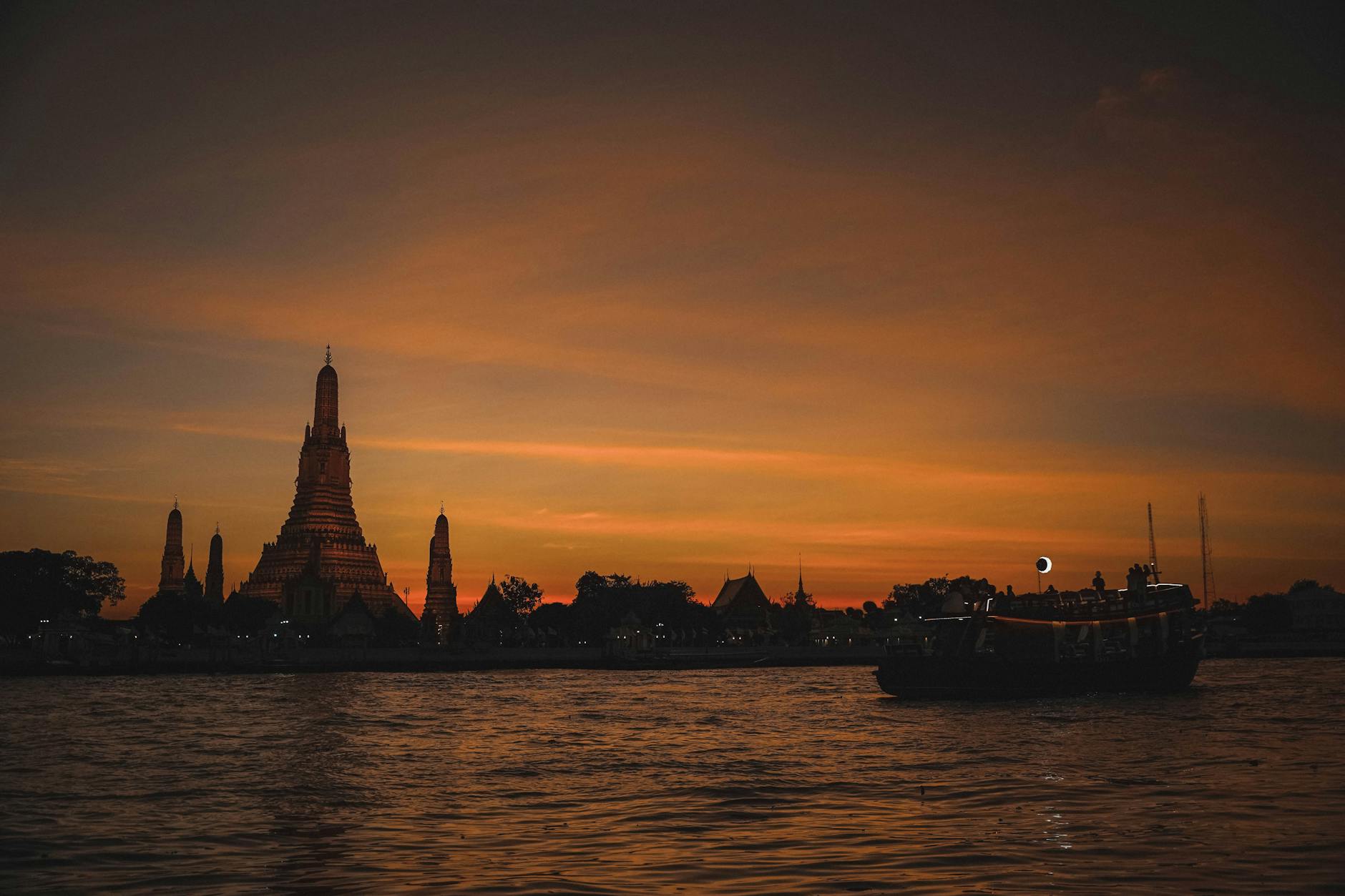 Bangkok riverside temple lit at dusk